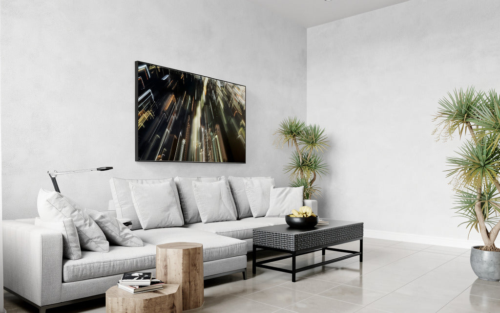 Modern living room with a white sofa, coffee table, and decorative plants and electric absract art piece on the wall.