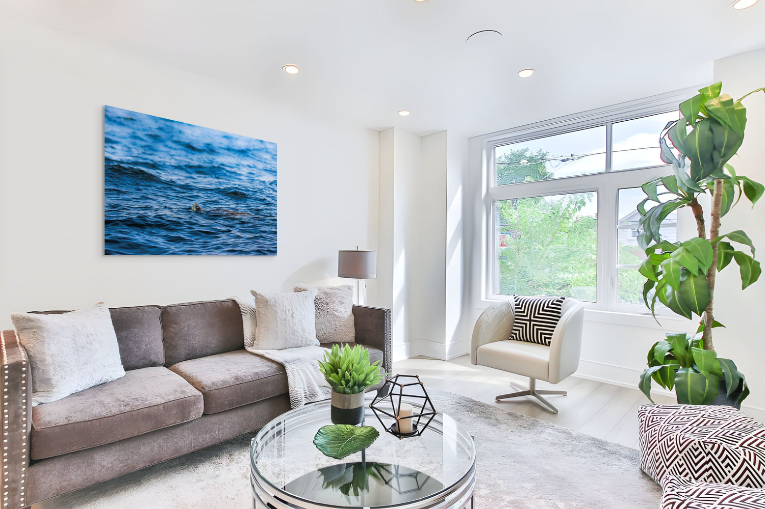 Modern living room with a gray sofa, glass coffee table, and large window and large acrylic ridley tortuga piece.